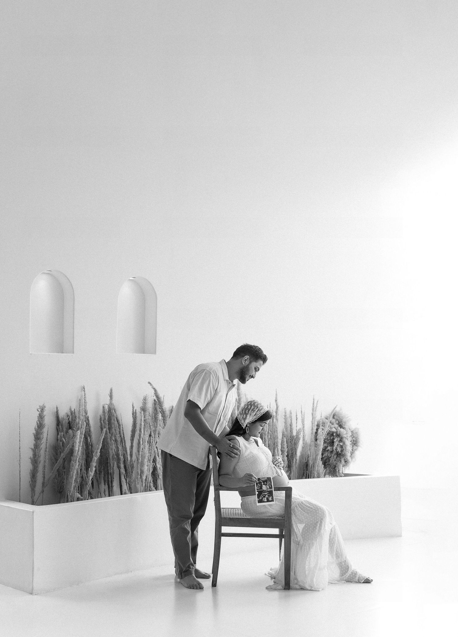 An artistic minimalist photo series showing a white gallery space with dark wheat grass installations against white walls.