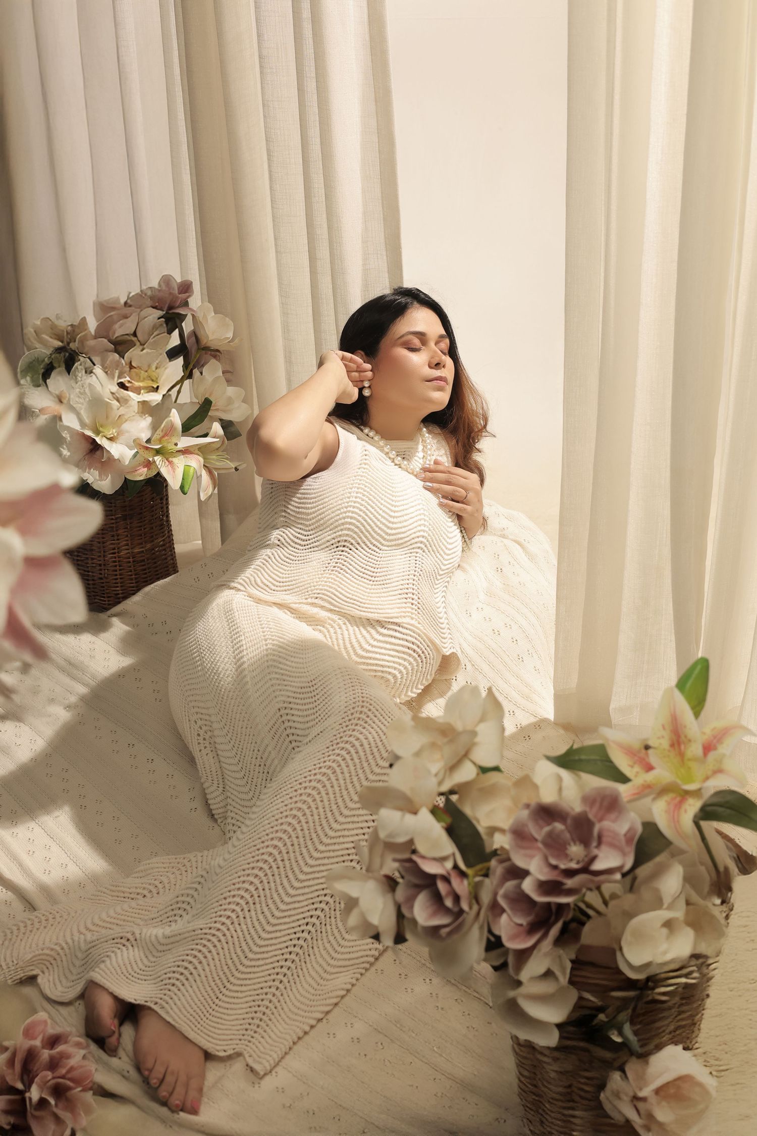 Artistic composition showing cream knit sweater and soft pink hydrangea flowers arranged with natural lighting.