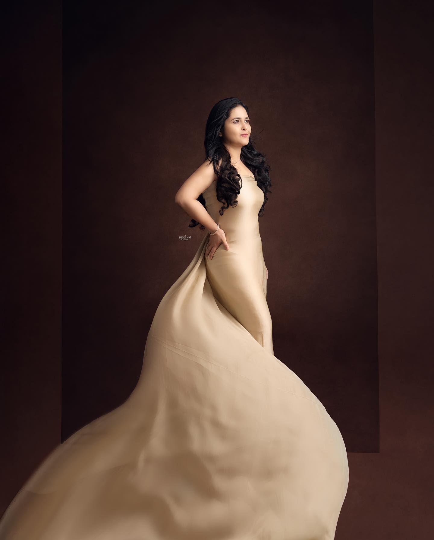 Dramatic studio maternity portraits with billowing beige fabric against a dark background.