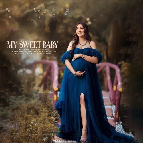 Expectant mother in flowing navy blue maternity gown poses outdoors in dreamy autumn setting with sunlit backdrop.