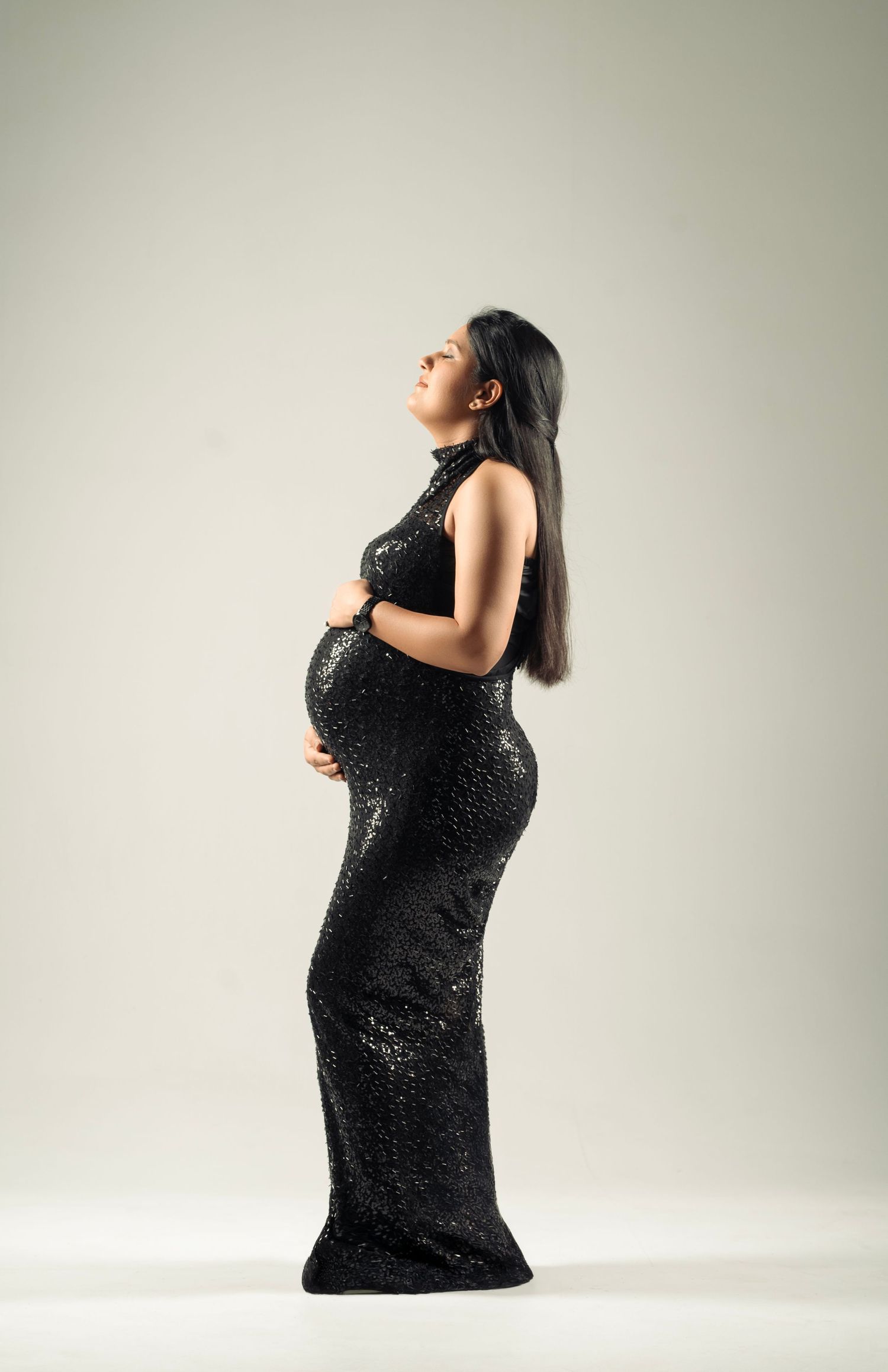 Silhouetted maternity portraits in sparkly black dress against neutral background.