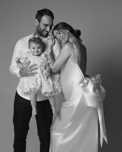 Sweet black and white family portraits showing tender moments between parents and baby in white dress.