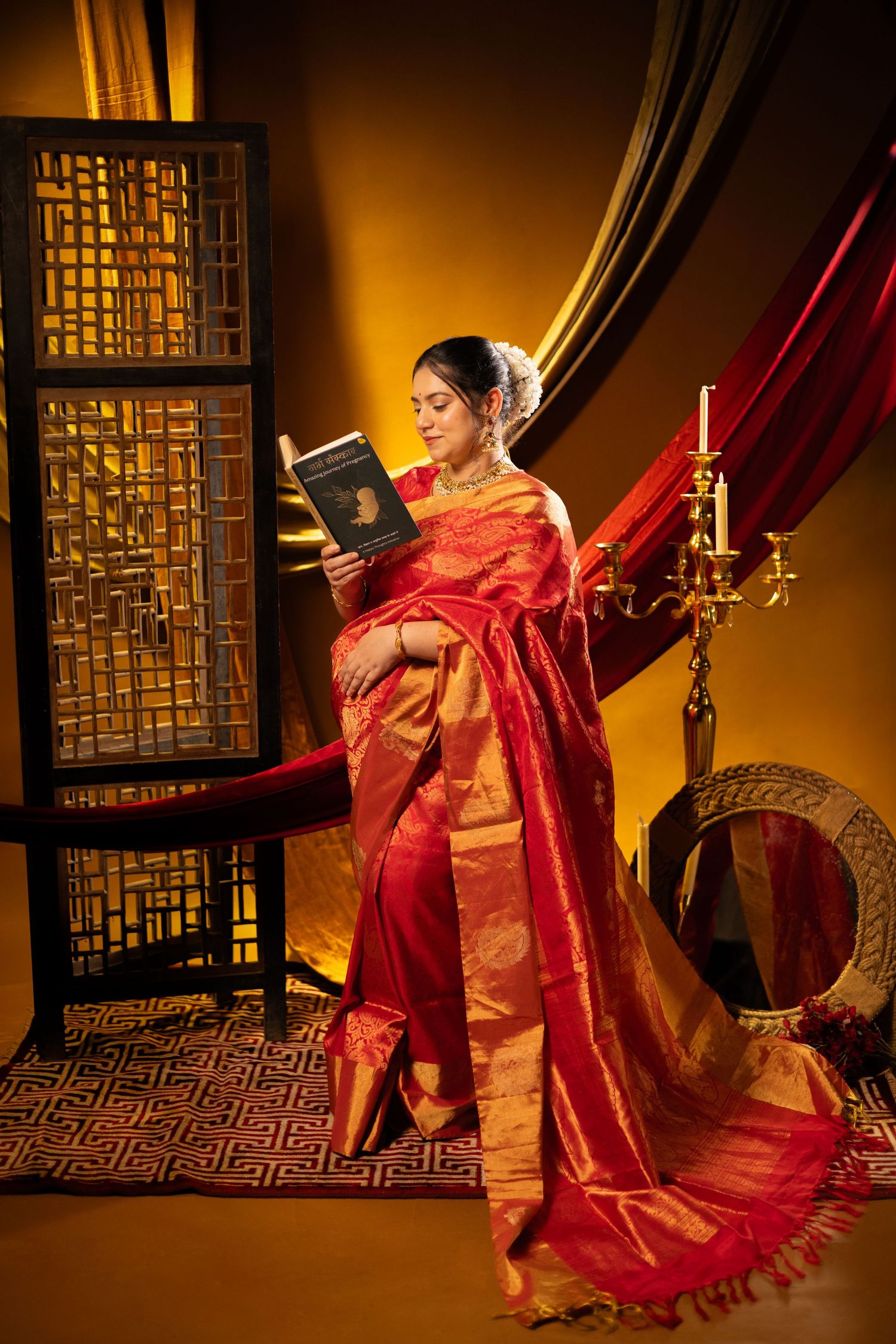 A dancer in a flowing red sari performs traditional Indian dance movements against a golden-lit backdrop with ornate screens.