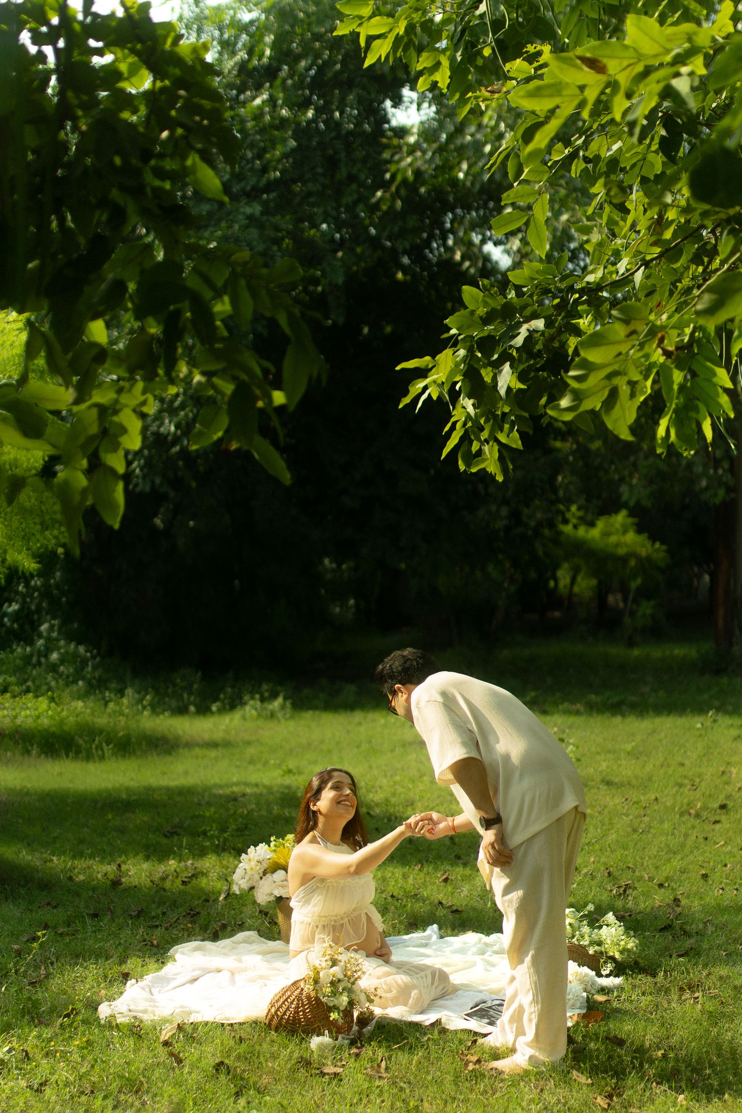 A romantic picnic scene unfolds in a sunlit garden with a couple sharing intimate moments on a blanket.