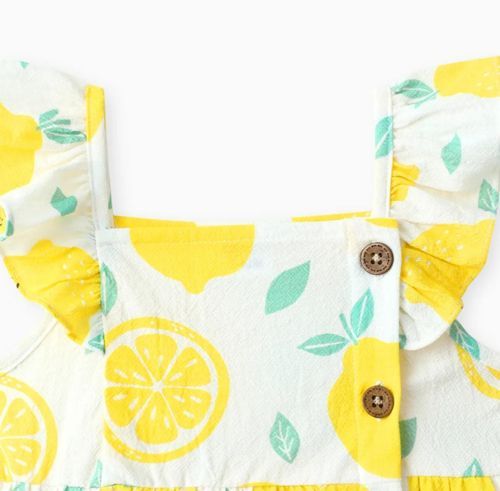 Yellow citrus print fabric with decorative buttons showing pattern detail.