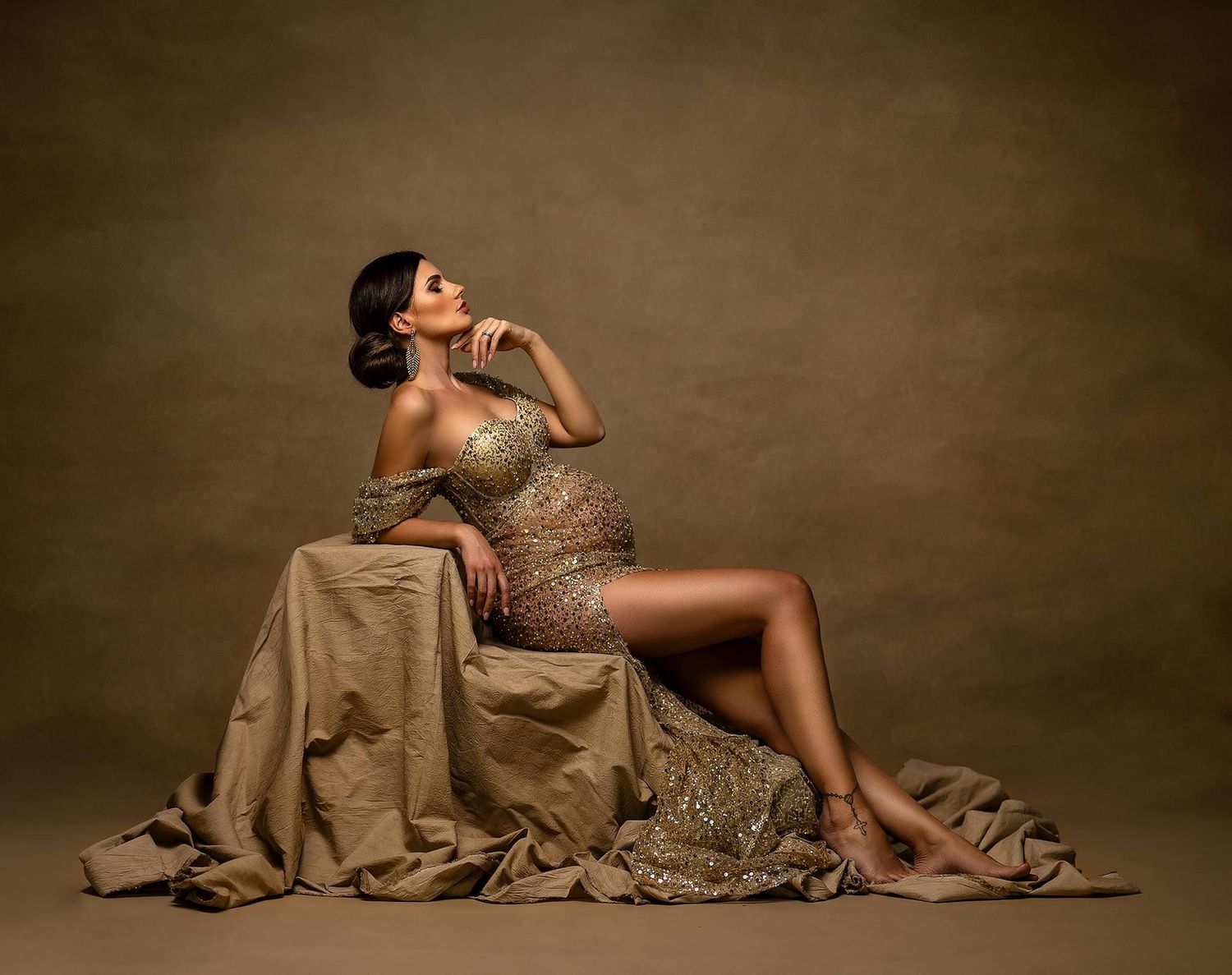 Dramatic maternity photography series with flowing fabric and artistic poses on studio floor.