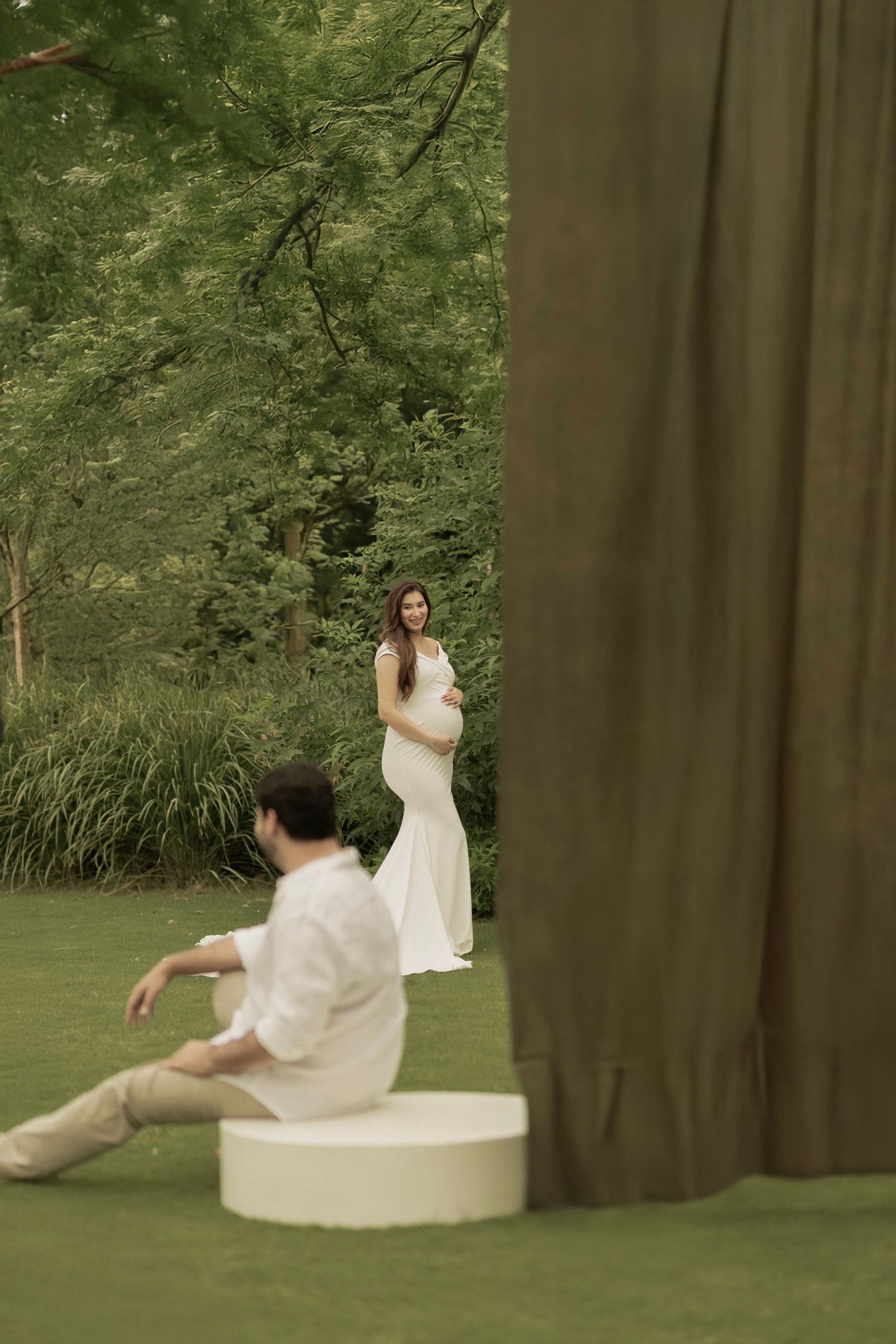 A series of artistic photos showing a person in white clothing reclining against a large tree trunk in a lush green forest.