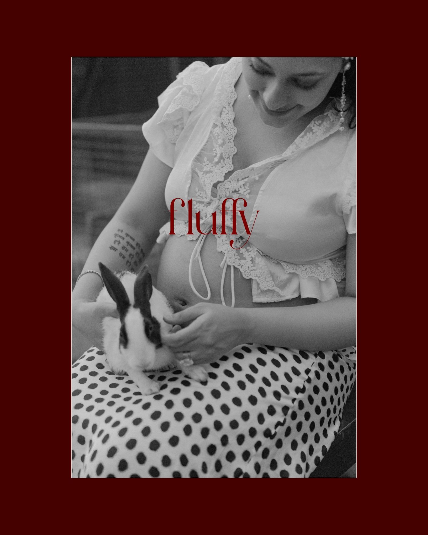 Woman in polka dot skirt holding a small rabbit, with Fluffy text overlay on black and white photo.