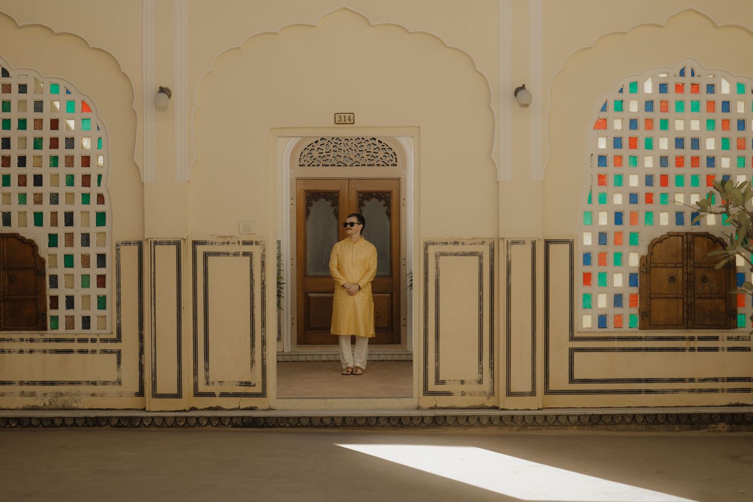 Panoramic view of an ornate mosque interior with colorful stained glass windows and white walls decorated with geometric patterns.