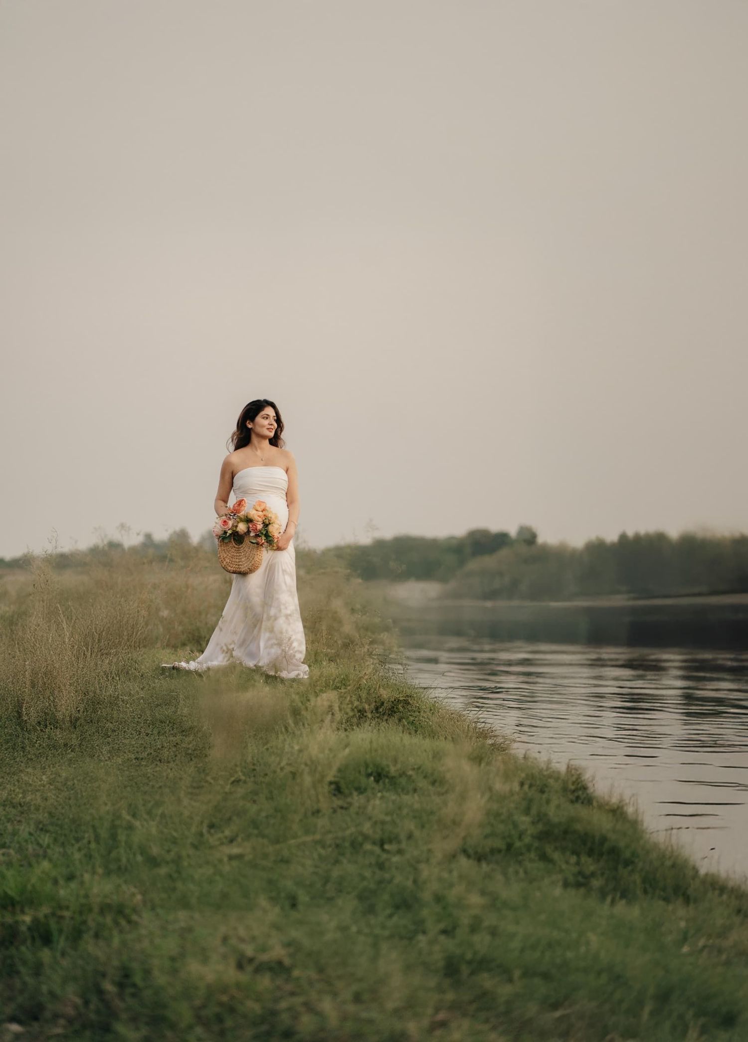Artistic maternity photos captured by a riverside with natural greenery and soft lighting.
