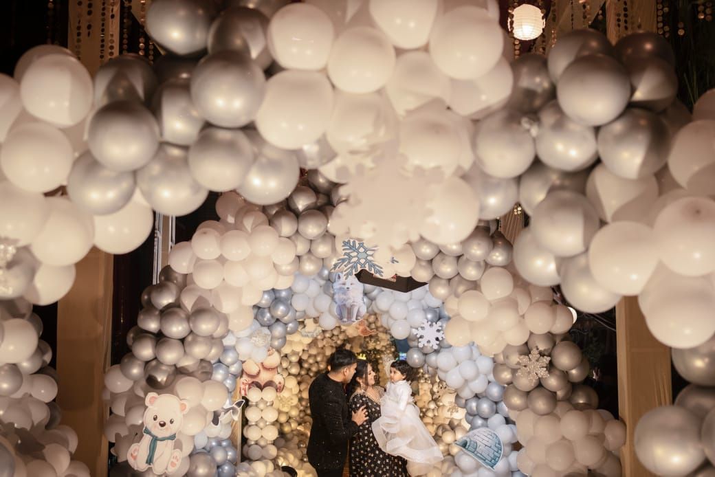 Couple poses romantically under an arch of white and silver balloons at an elegant wedding venue decoration.