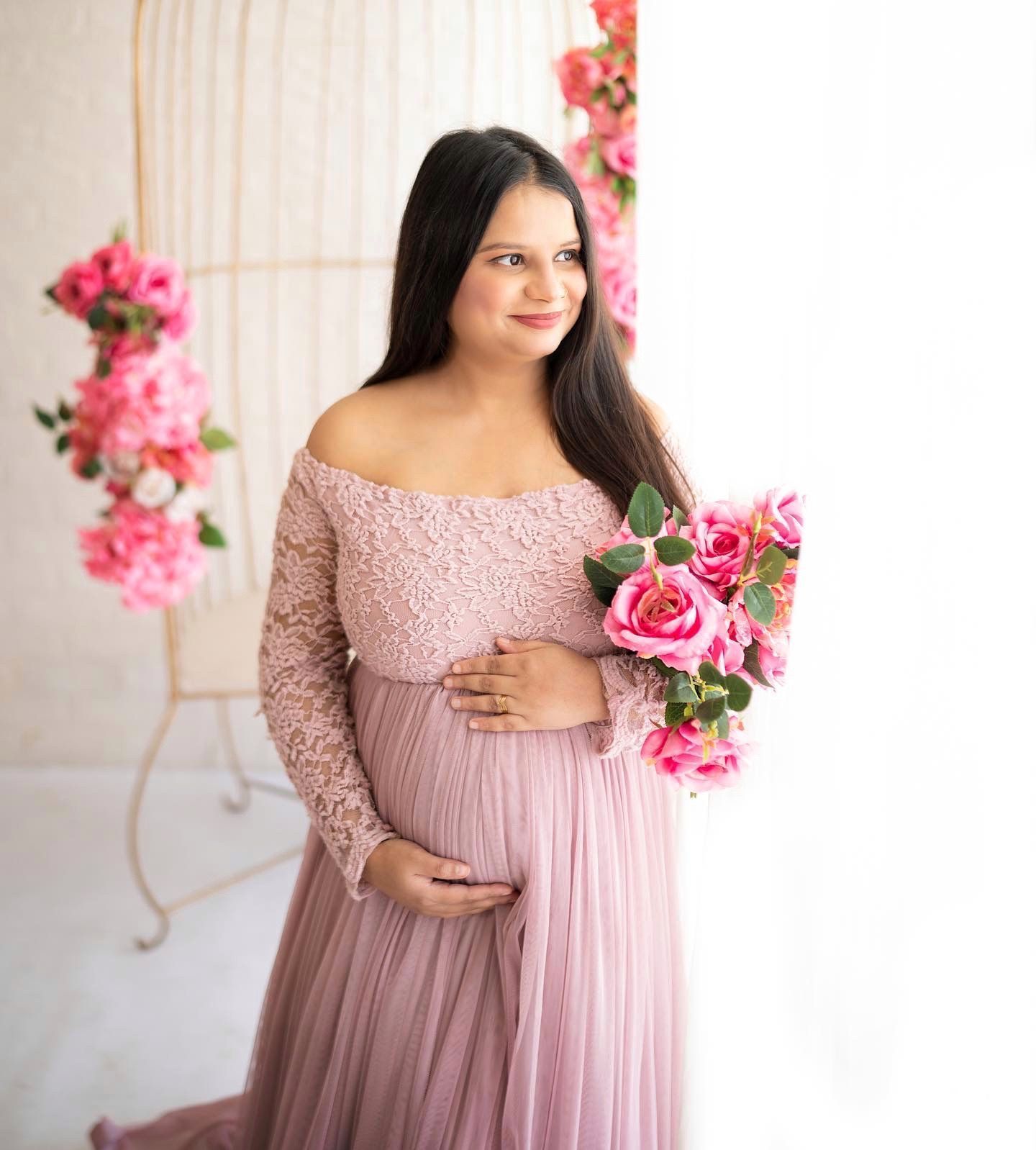 Feminine maternity photography with pink lace dress and rose flower decorations.