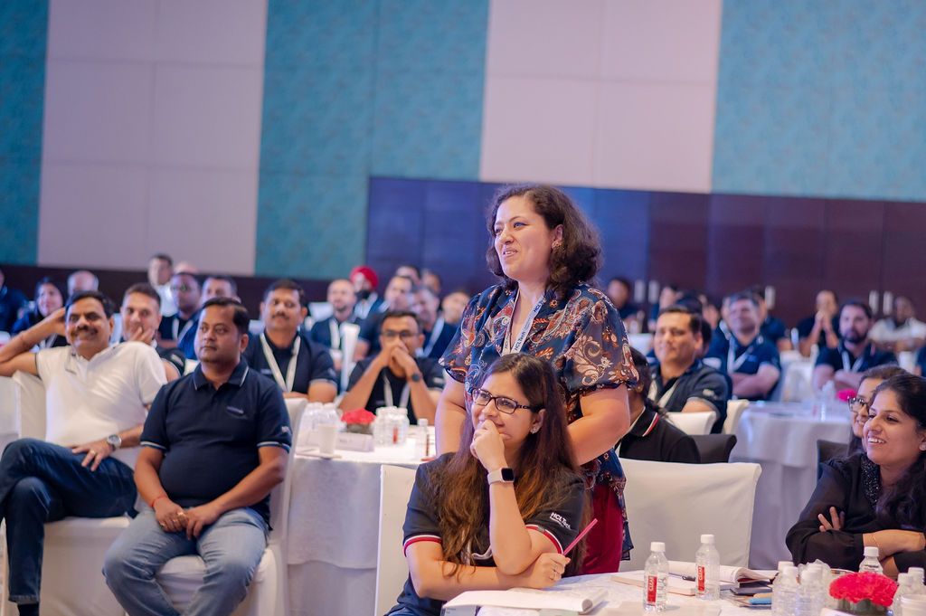 Audience members engage during a business conference presentation in a modern corporate setting.