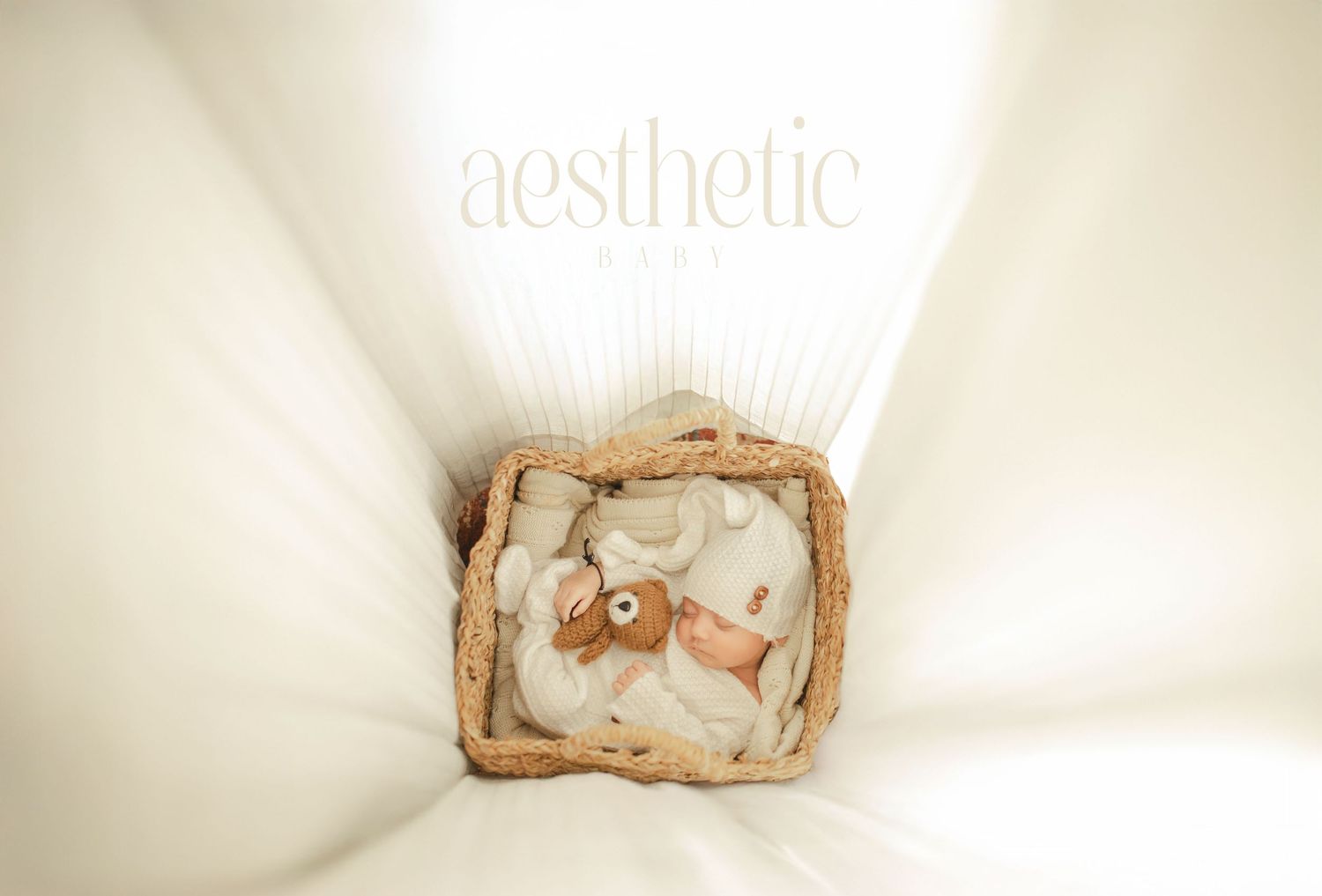 Newborn baby sleeping peacefully in a woven basket with a teddy bear, wrapped in white, for Aesthetic Baby photography.