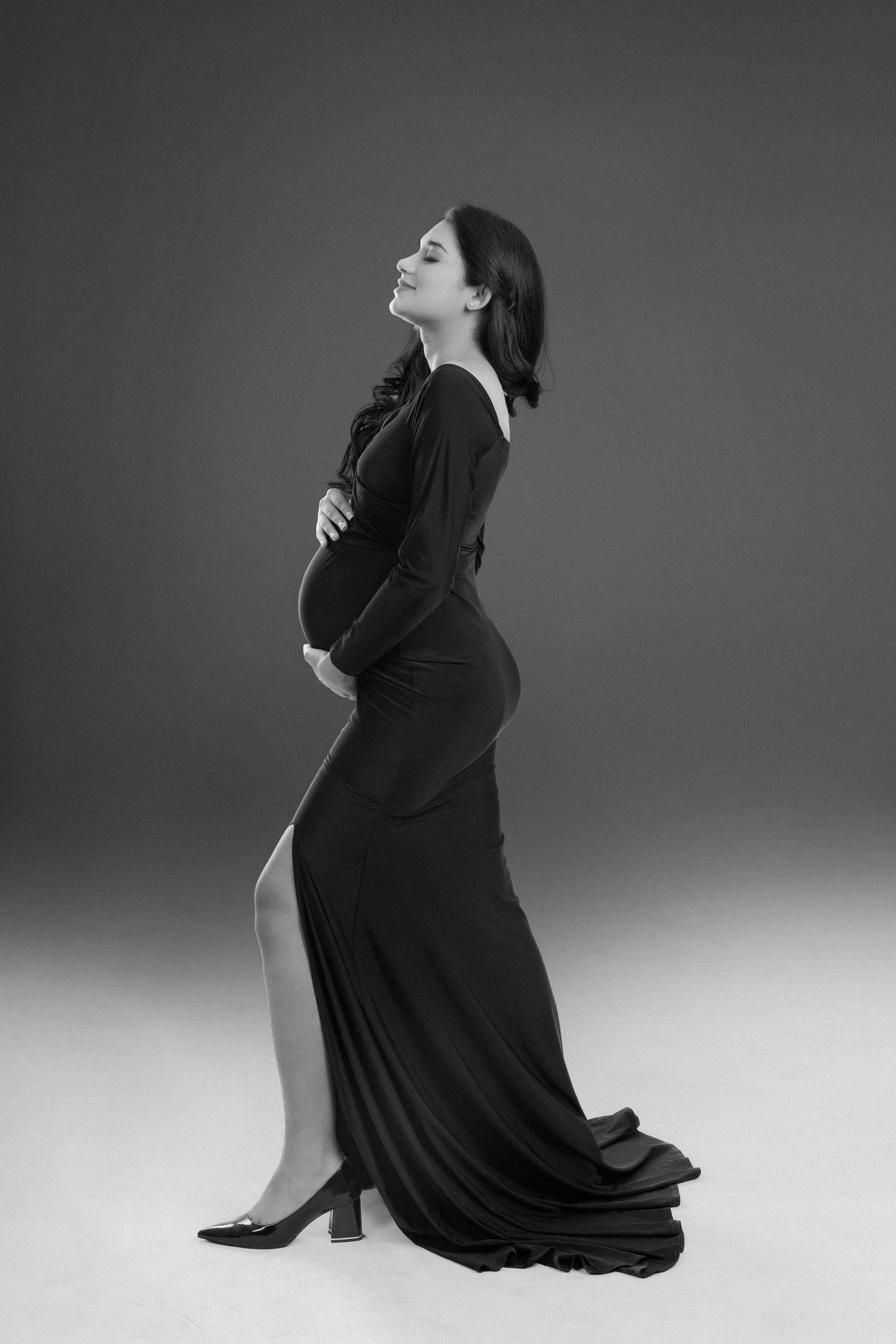 Dramatic black and white maternity photos showing elegant poses on studio floor.