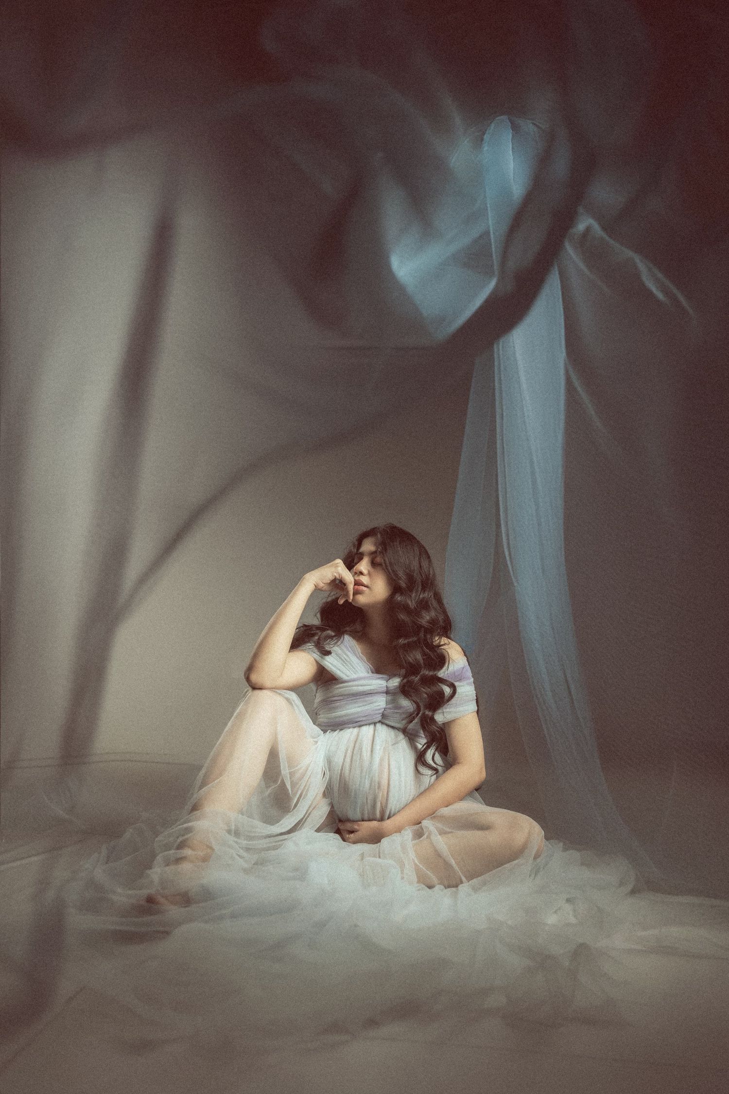 Artistic maternity series with dramatic shadows and billowing white fabric.