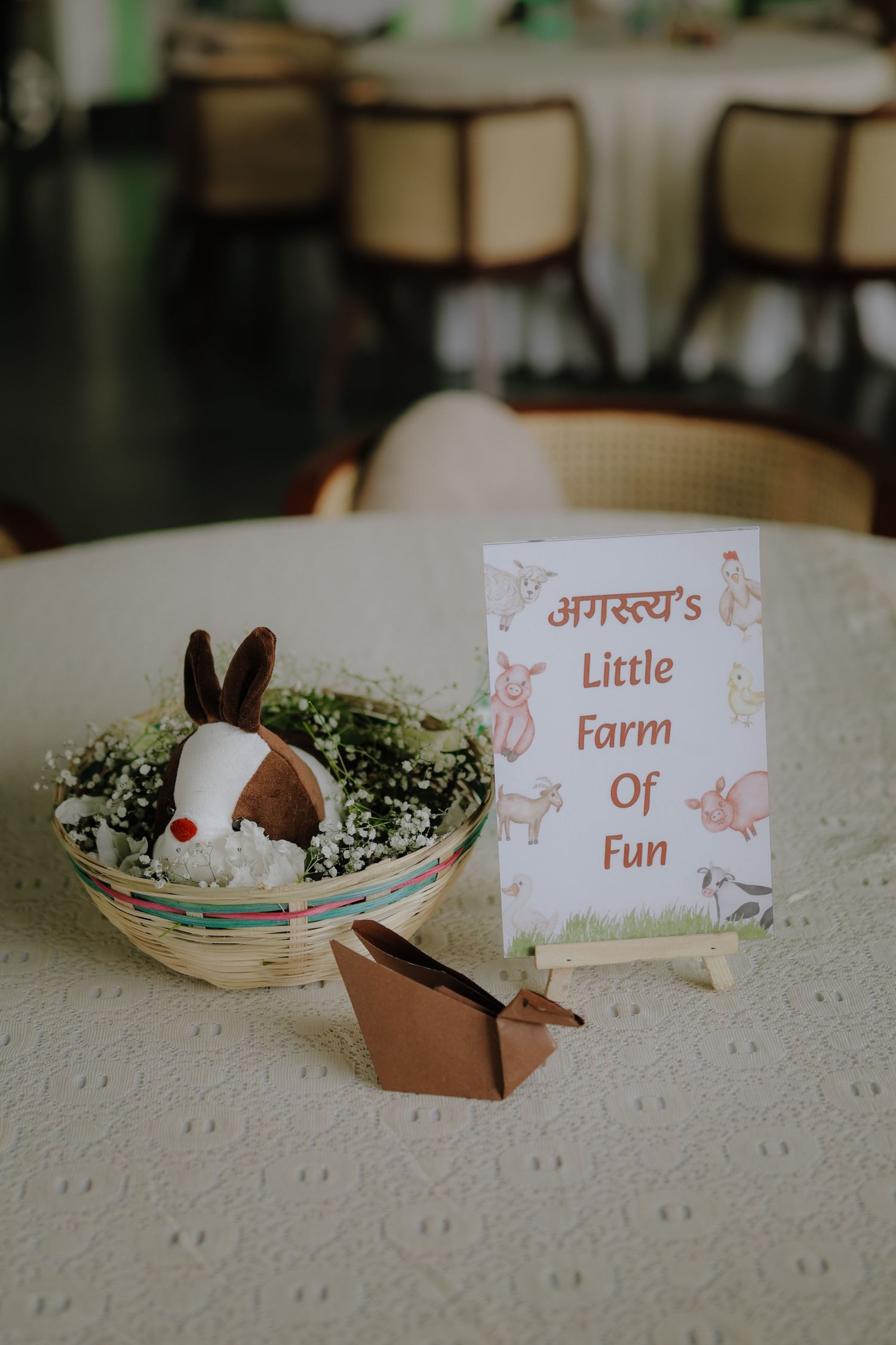 A farm-themed party table centerpiece featuring a stuffed bunny in a basket with baby's breath flowers and a Little Farm of Fun sign.
