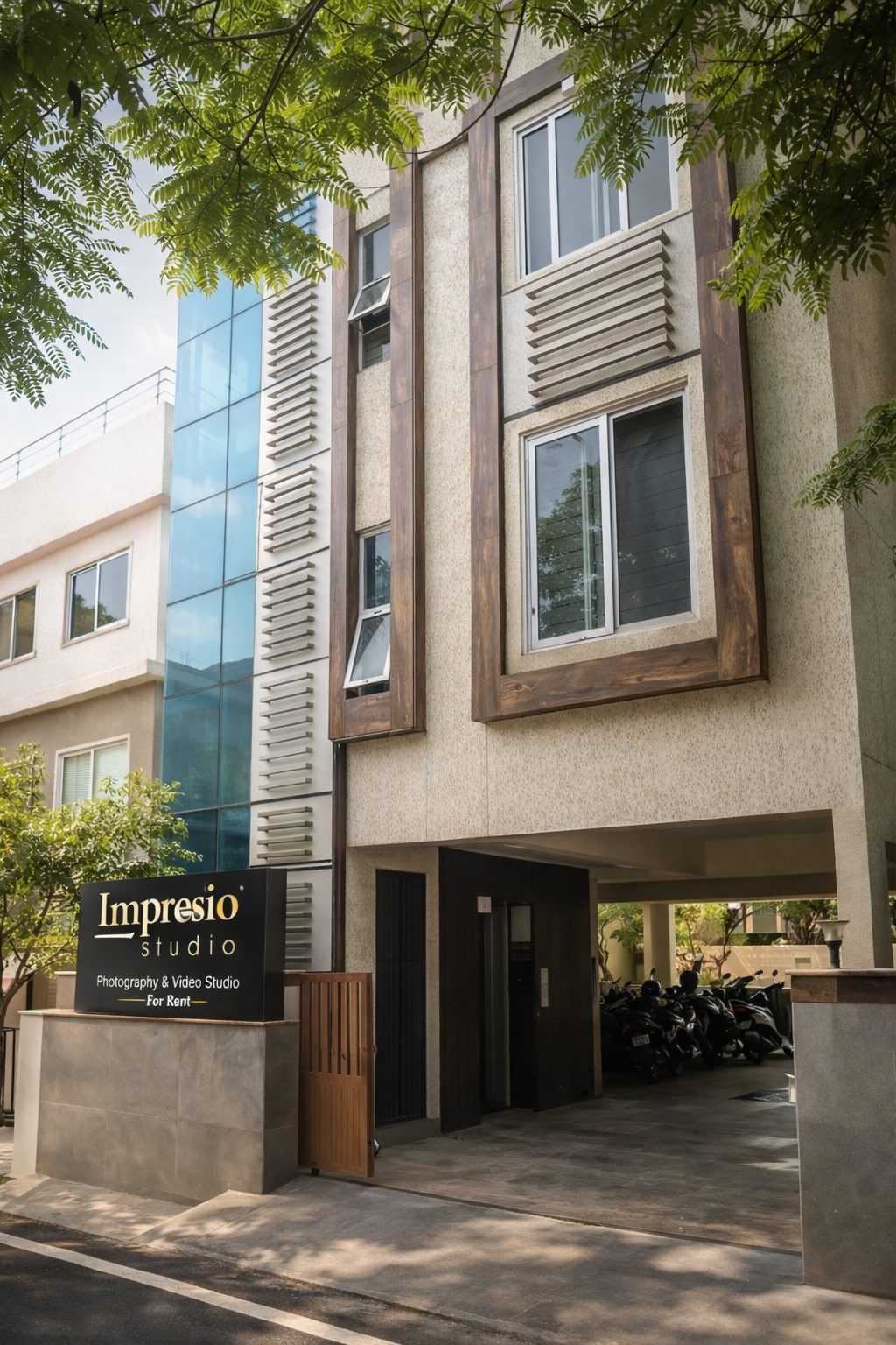 Modern commercial building exterior with glass windows and tree-lined walkway showing multiple entrance angles.