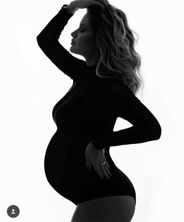 Minimalist black and white silhouette of pregnant figure in profile pose.