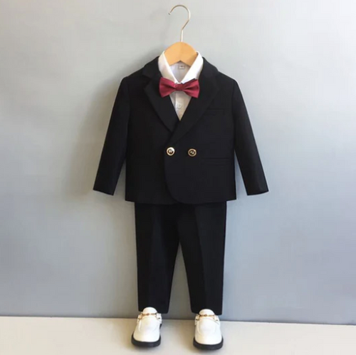 Black formal toddler suit with red bow tie and white dress shoes.