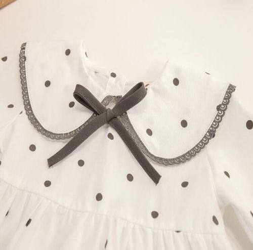 Close-up of white polka dot fabric with grey trim details.