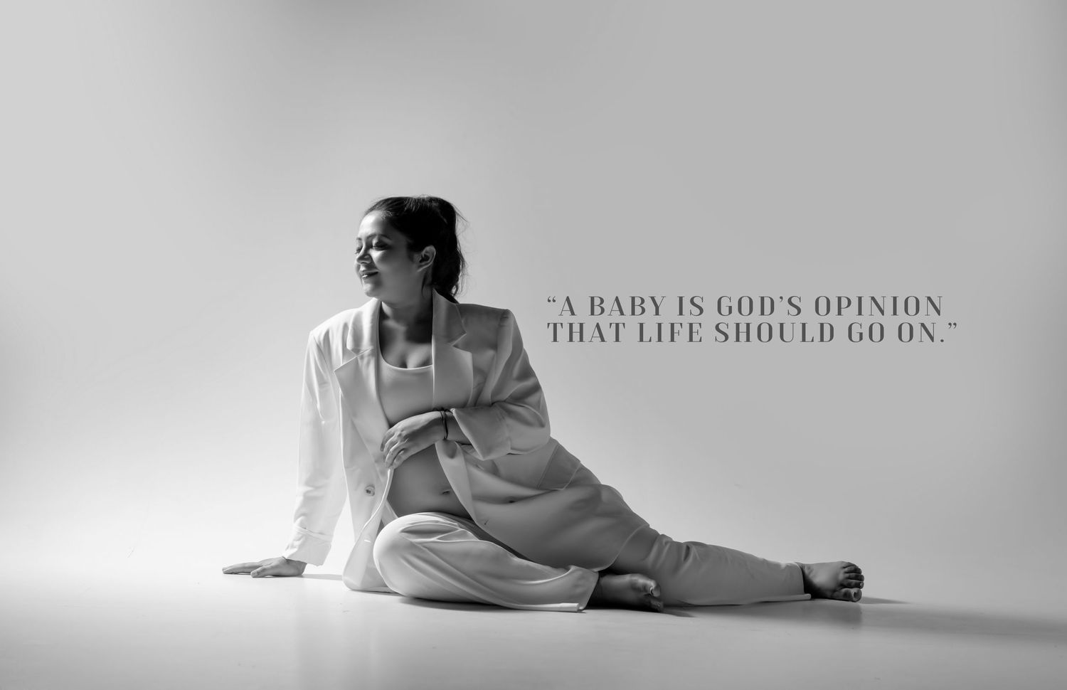 Artistic maternity photography with text overlay in grayscale.