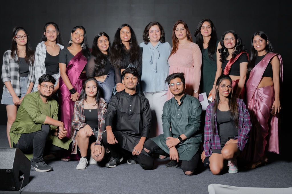 Group of students posing together for photos against a dark wall at a social event or gathering.
