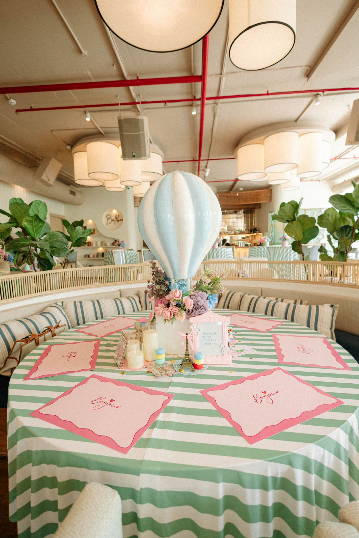 Elegant baby shower table with mint chevron tablecloth, hot air balloon centerpiece, and pink place cards in a chic restaurant.