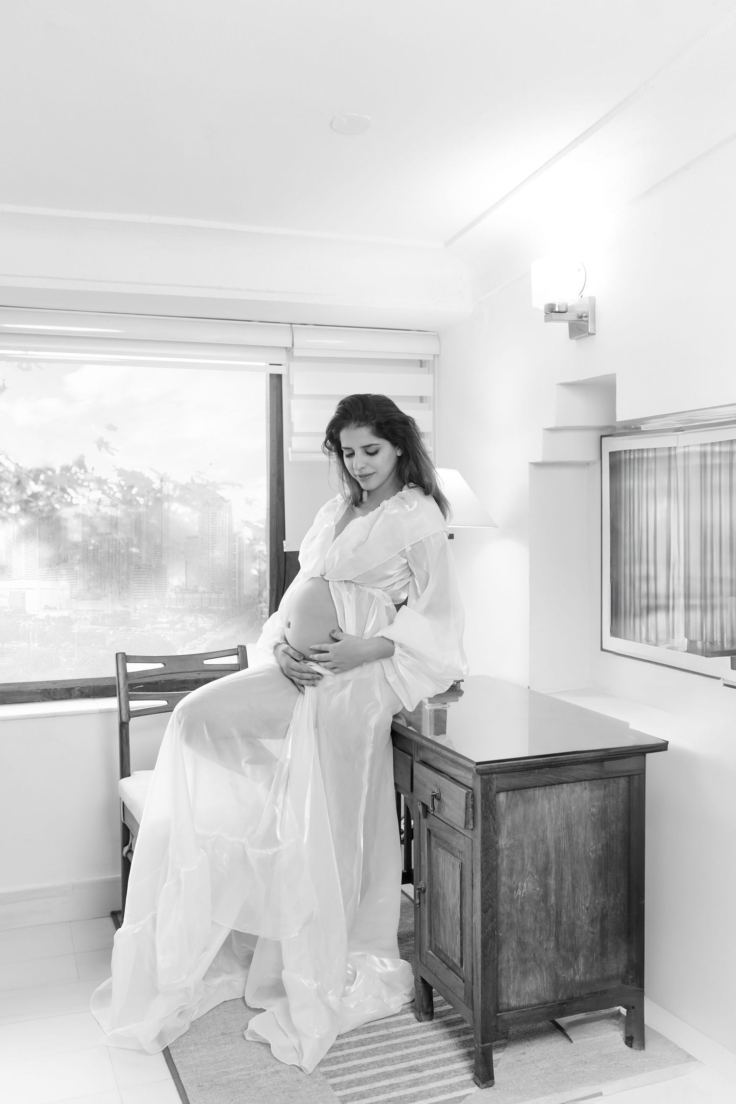A series of black and white photos showing a person in a white flowing dress moving through a minimalist interior space.