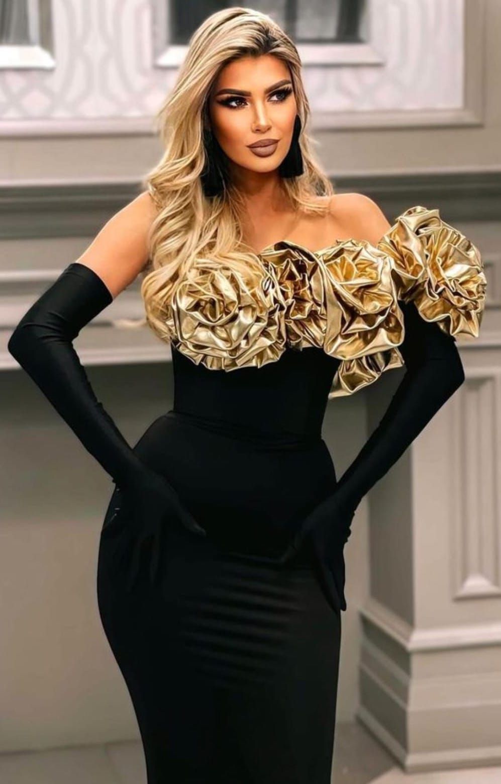 Glamorous evening gown with gold ruffle detail and black long gloves in an elegant indoor setting.