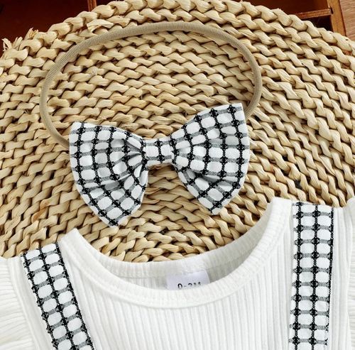 White ribbed top with black and white gingham bow and trim details on woven placemat.