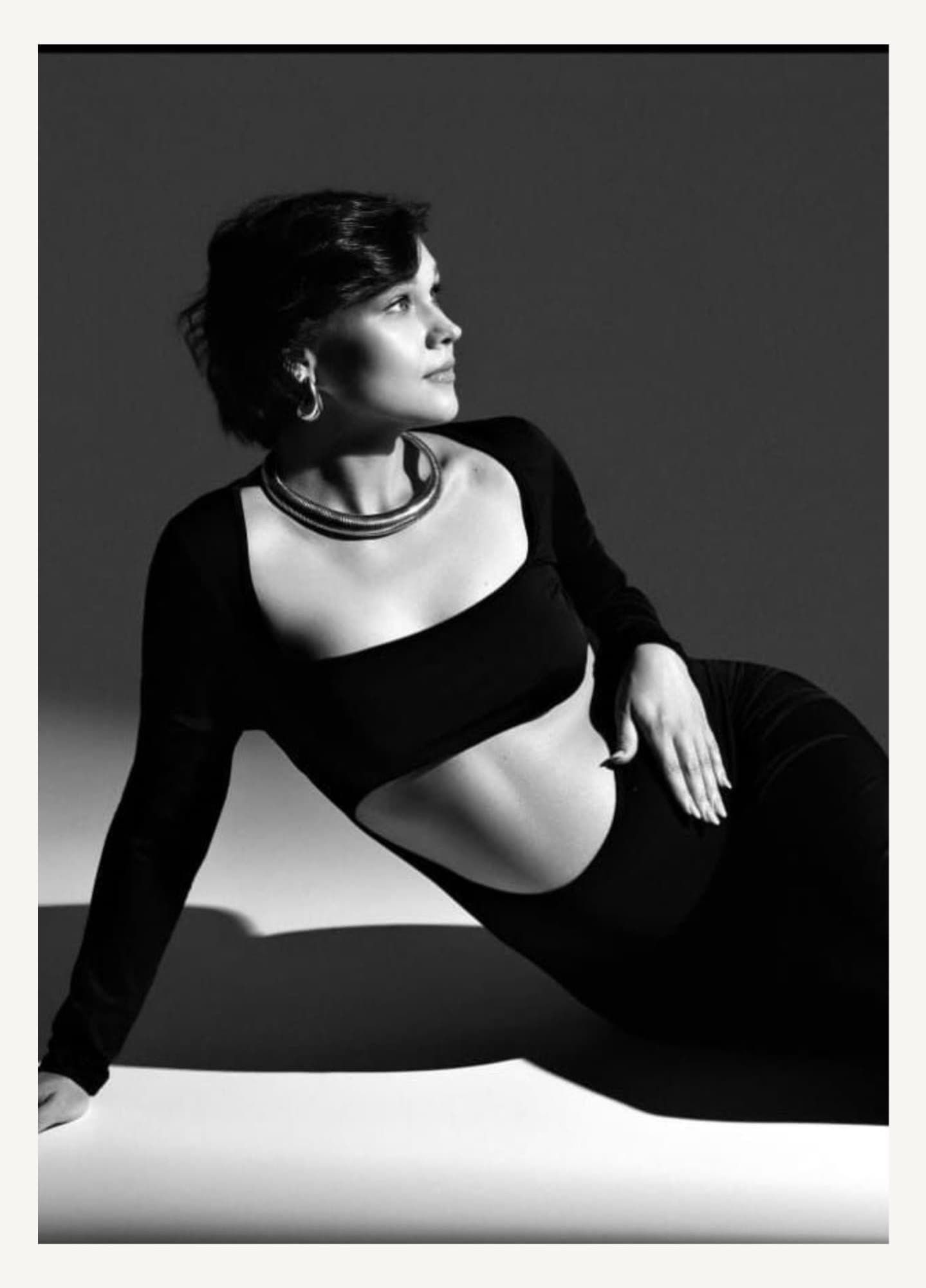 Dramatic black and white maternity photos with artistic poses against studio lighting.