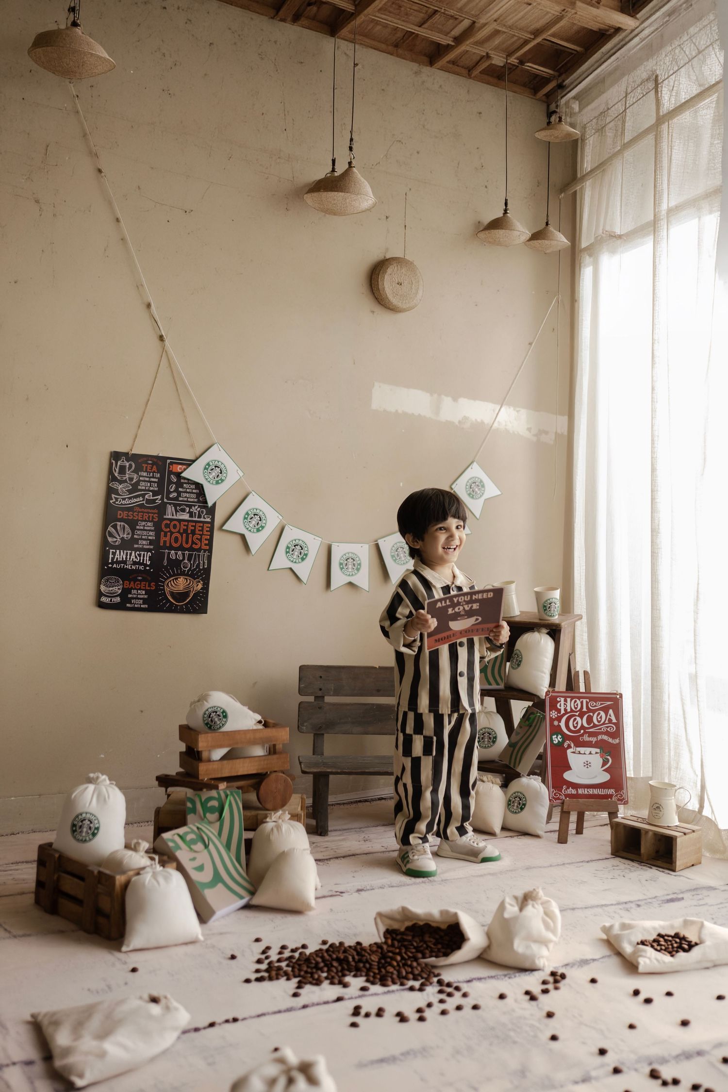 A young boy in striped pajamas stands in a cozy cafe-themed room with coffee beans and Starbucks decor.