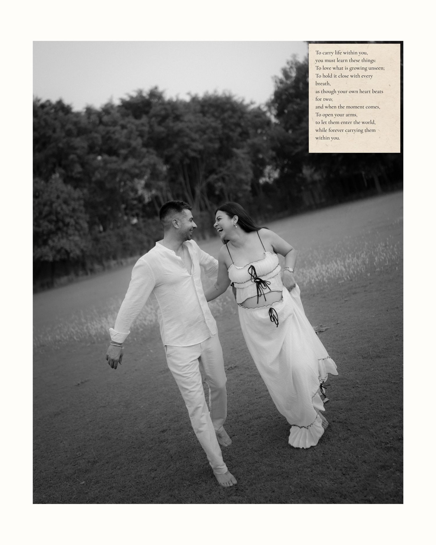 Black and white photo of a couple in white outfits walking hand in hand through a grassy field at dusk.