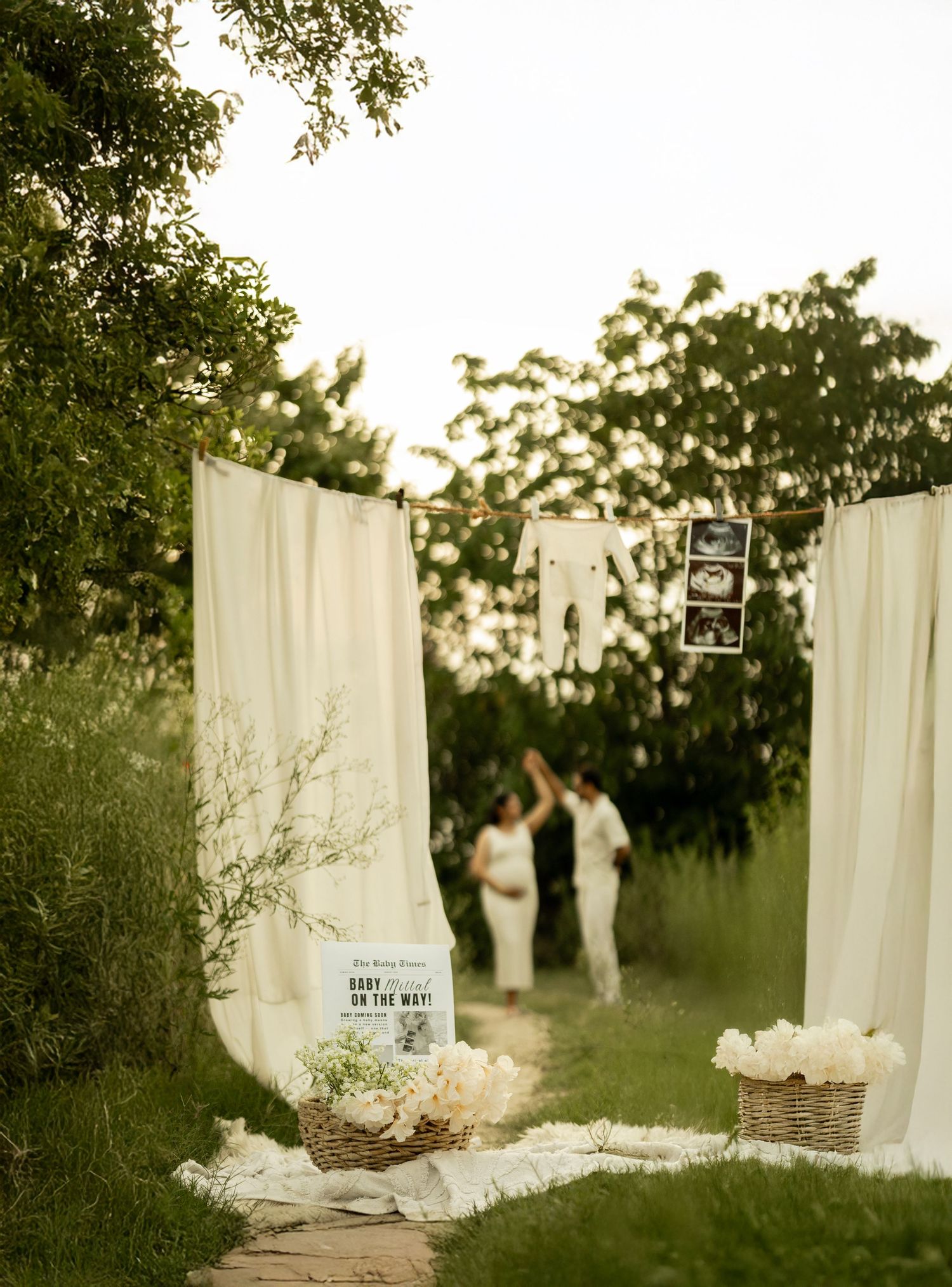 White curtains hanging between trees create an ethereal outdoor photo setting at sunset.