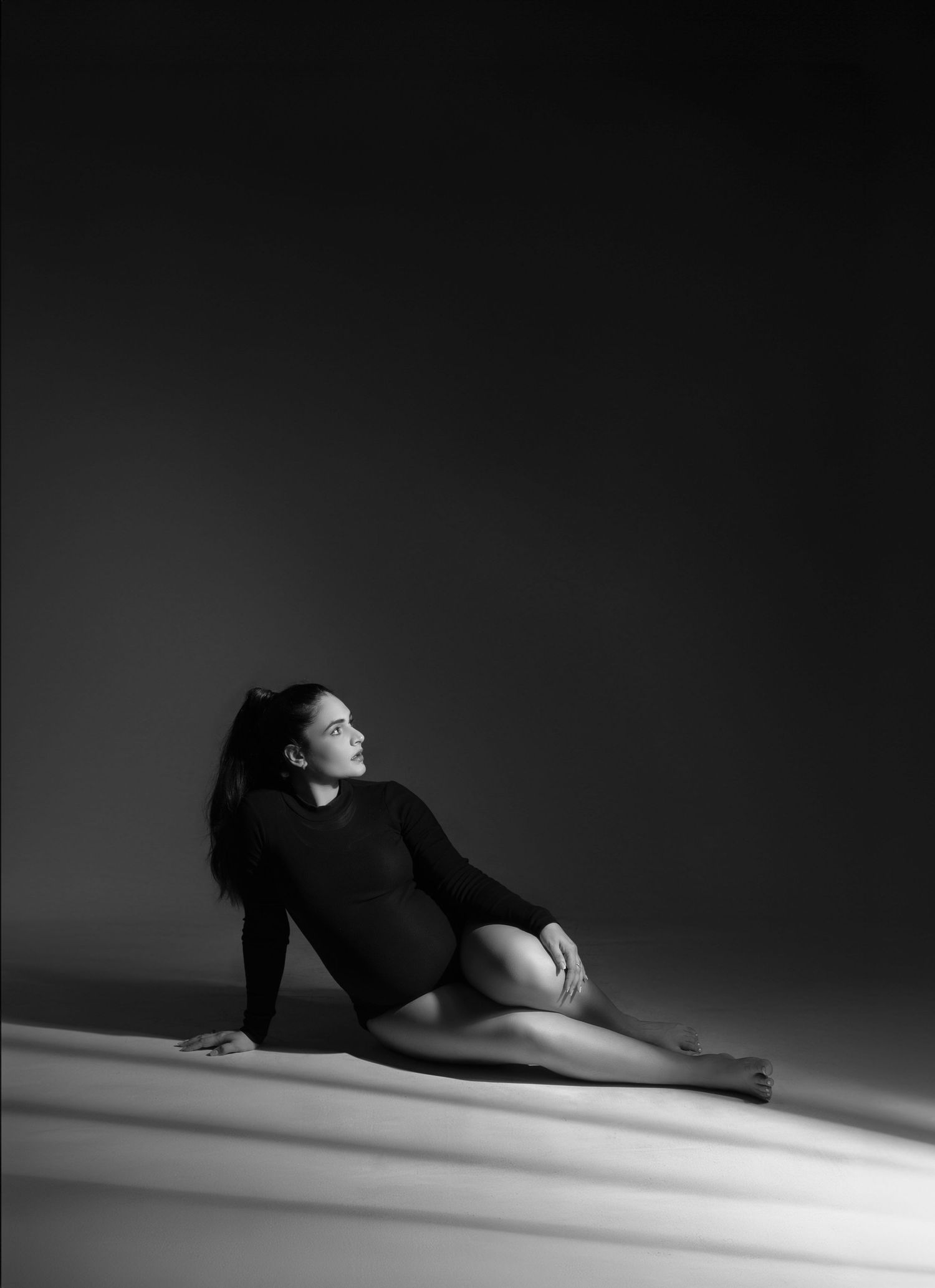 A dramatic black and white photo series showing a figure in black clothing moving gracefully across a light floor.