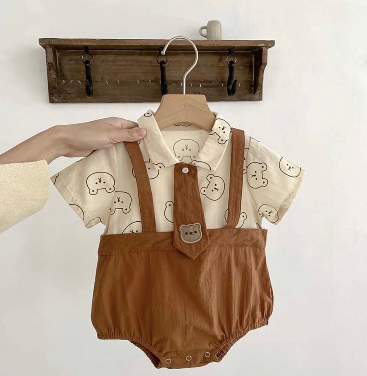 Four sequential images showing a brown leather baby romper with white collar displayed on wooden hangers.