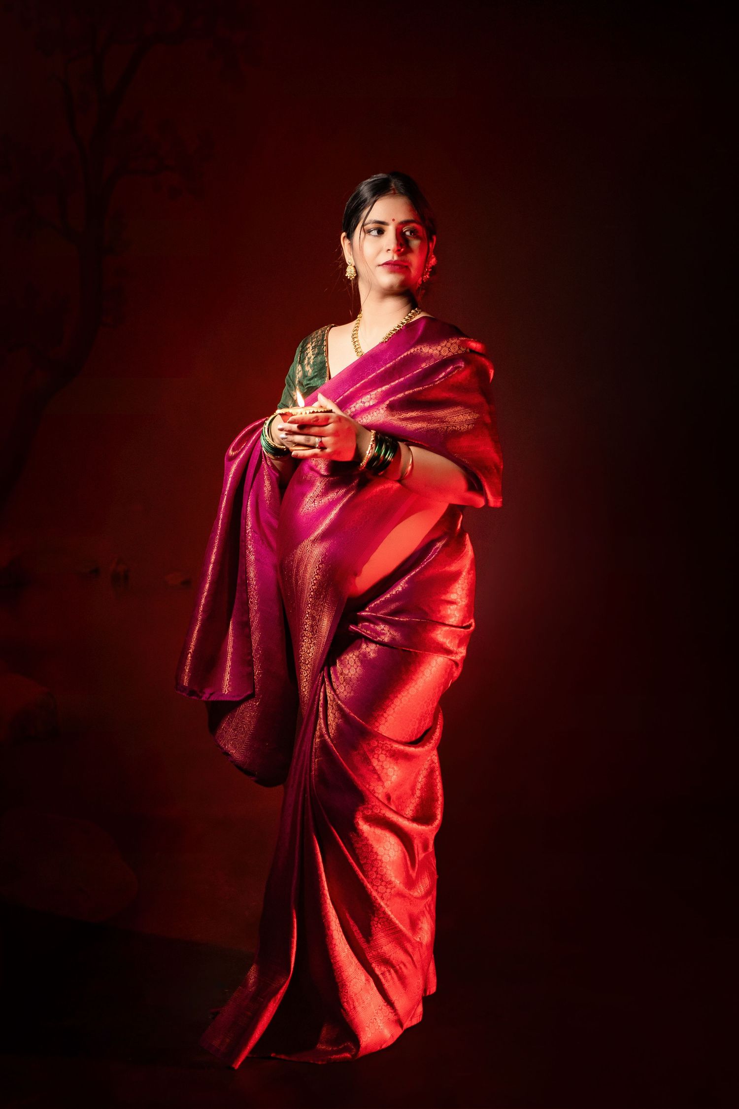 Artistic maternity portrait series in vibrant red fabric against dark background with dramatic lighting.