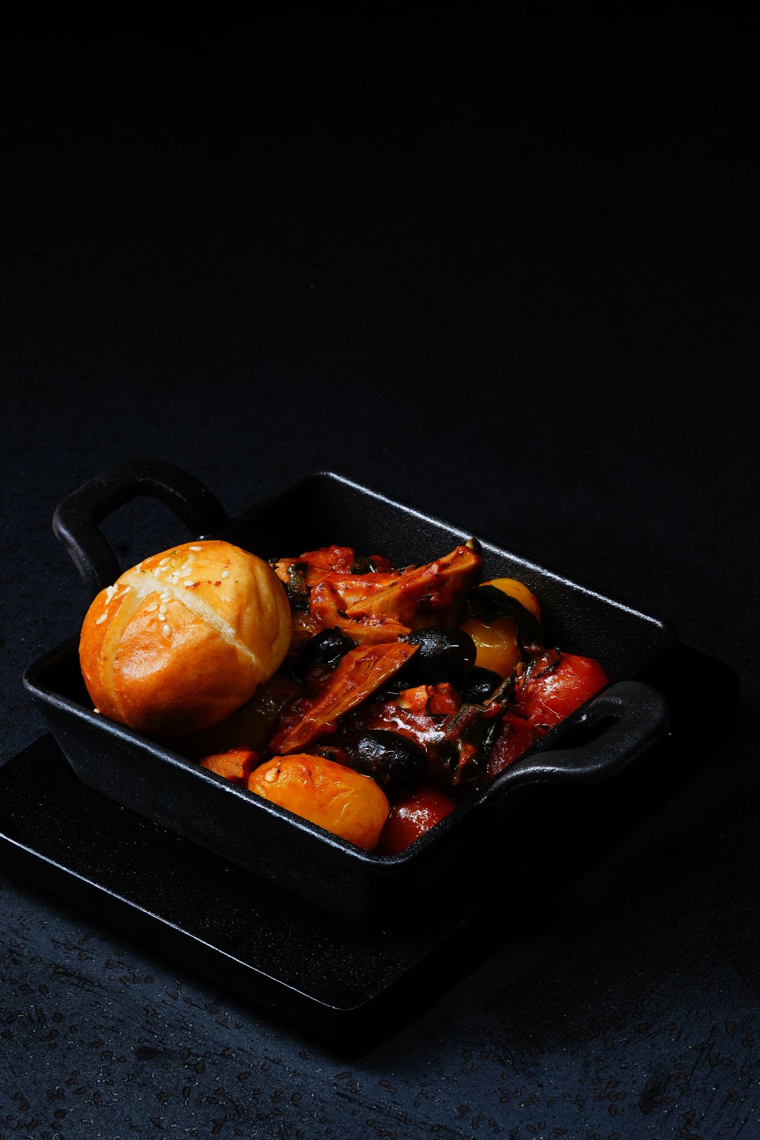 Grilled vegetables and meat skewers with orange sauce in black rectangular plate.