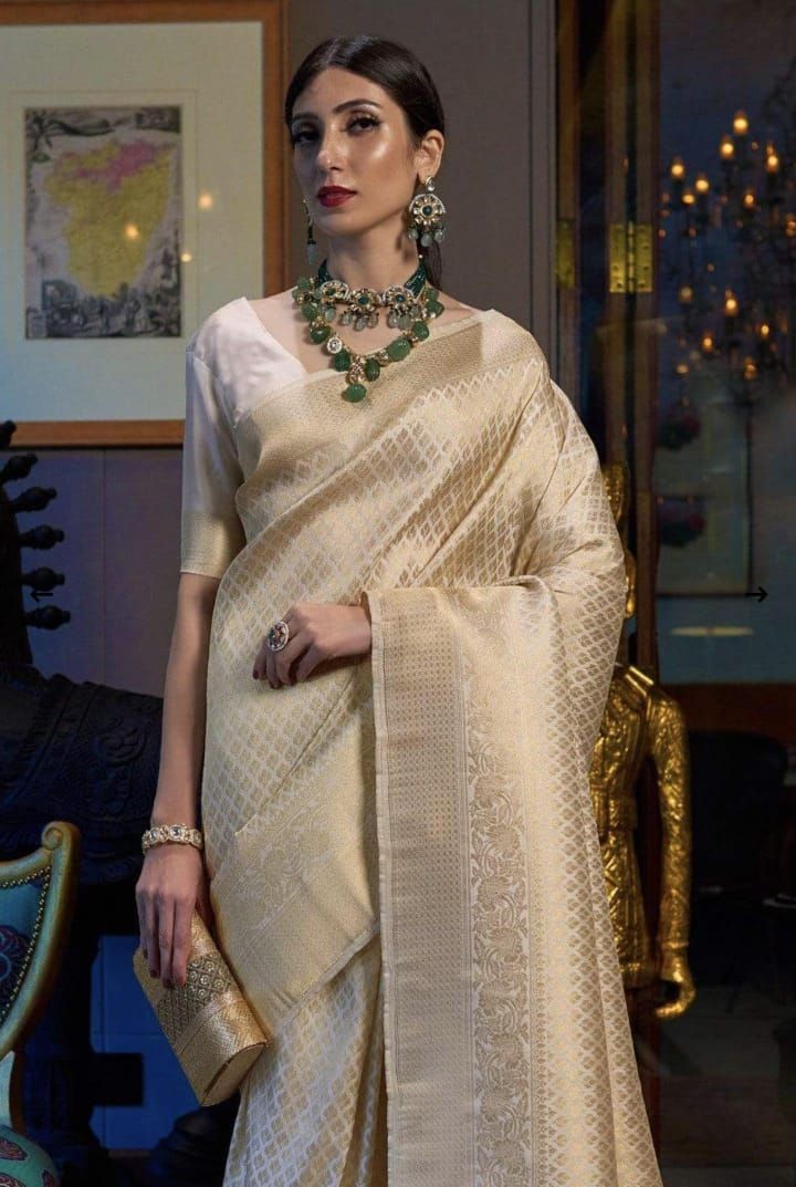 Elegant cream-colored silk saree with detailed zari work and geometric patterns.