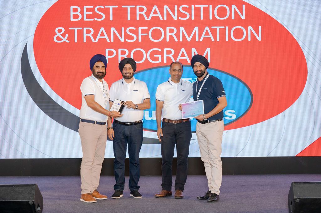 People gathered on stage with red signage about transition and transformation at a business conference.