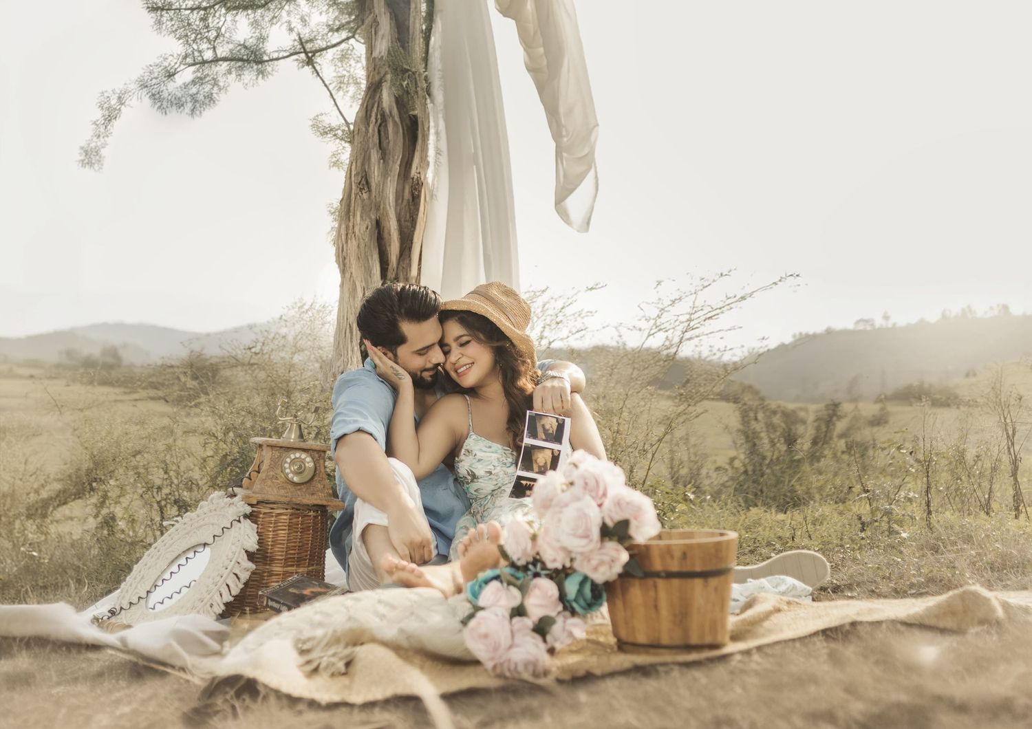 Couple photos in nature with vintage decor, soft colors, and rustic elements creating a dreamy outdoor atmosphere for maternity shoot.