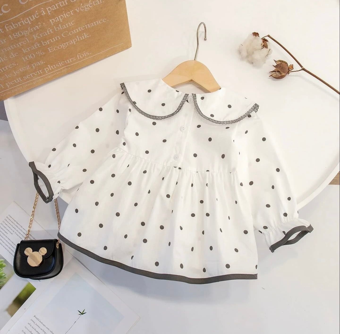 Polka dot Peter Pan collar with black and white pattern displayed on white fabric lighting flat lay arrangement.