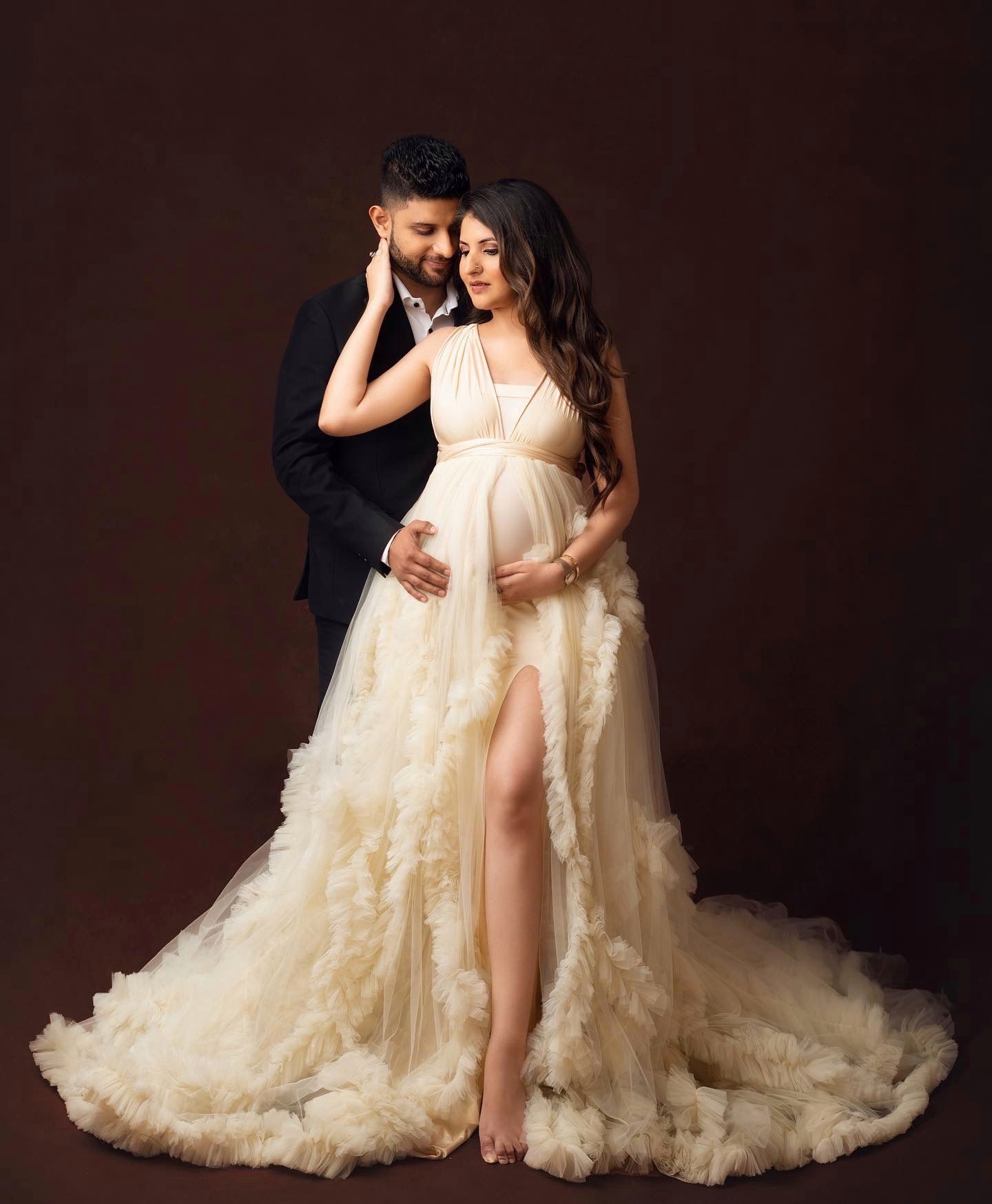 An intimate maternity portrait featuring a cream-colored ruffled gown with dramatic train.