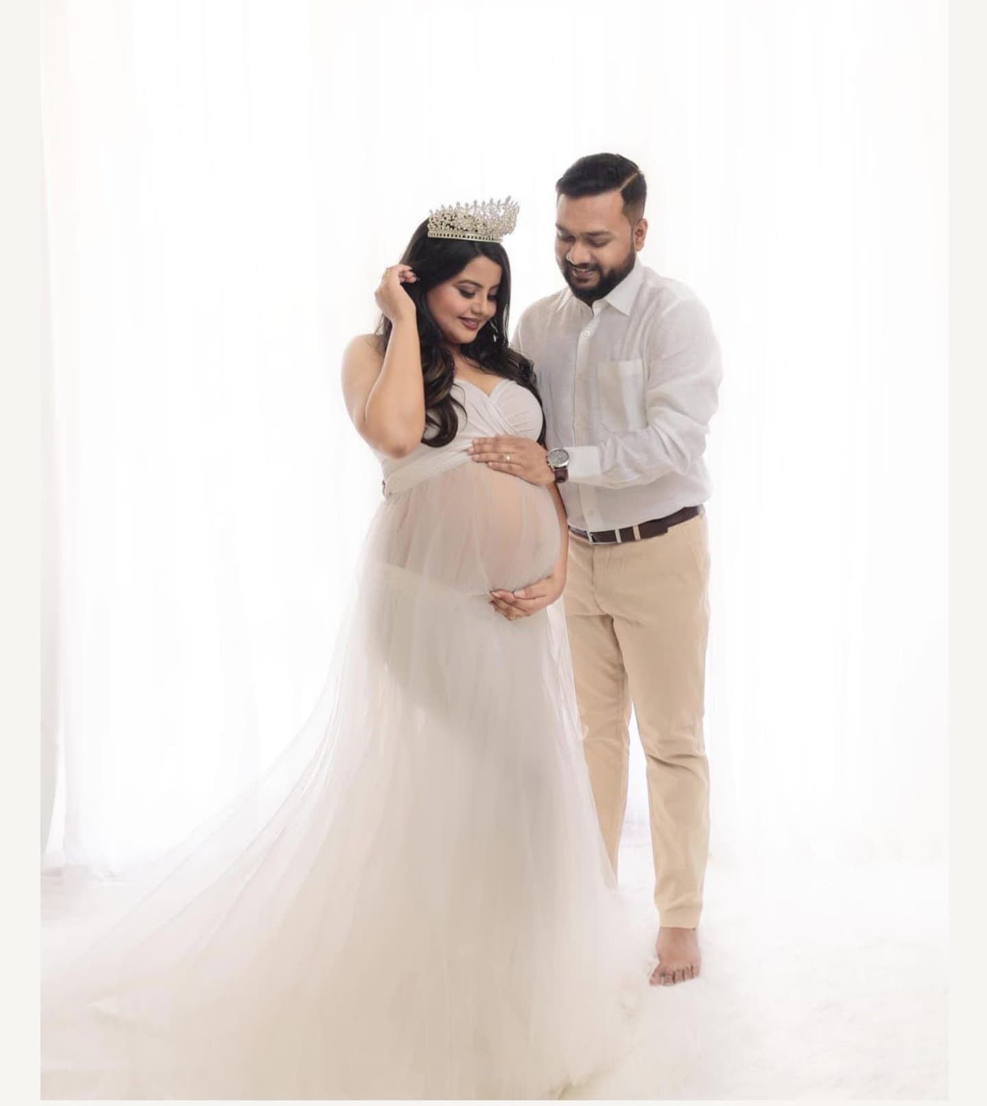 Bright white maternity session featuring couple in coordinated neutral outfits.