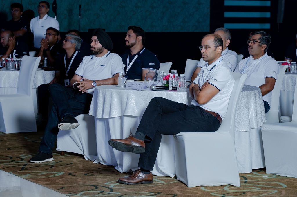 Business professionals seated at tables in a conference room during a corporate event or meeting.