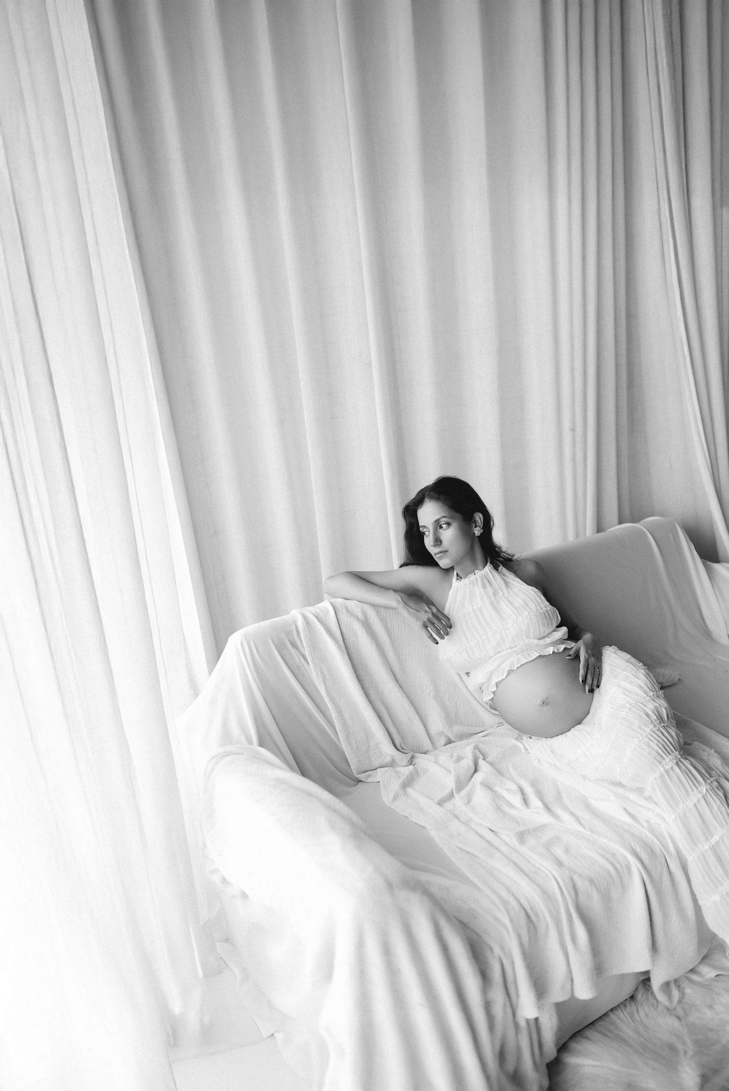 A series of white curtained windows with rumpled bedding and pillows creating a dreamy, ethereal atmosphere.