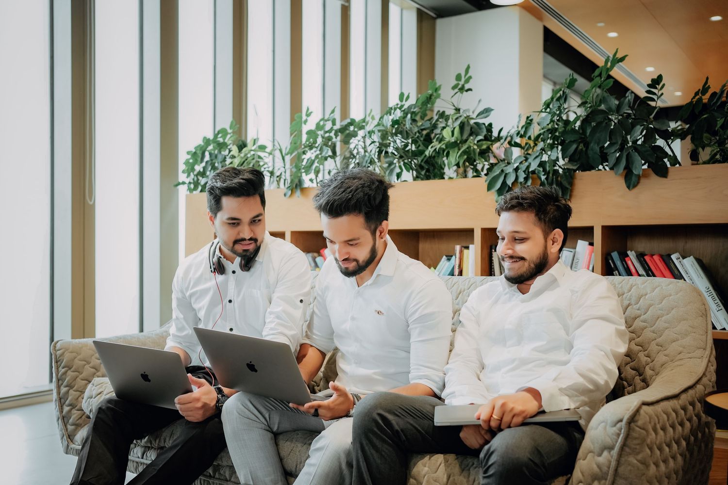 A group of people sitting on a couch and laughing together in a bright, modern office space.