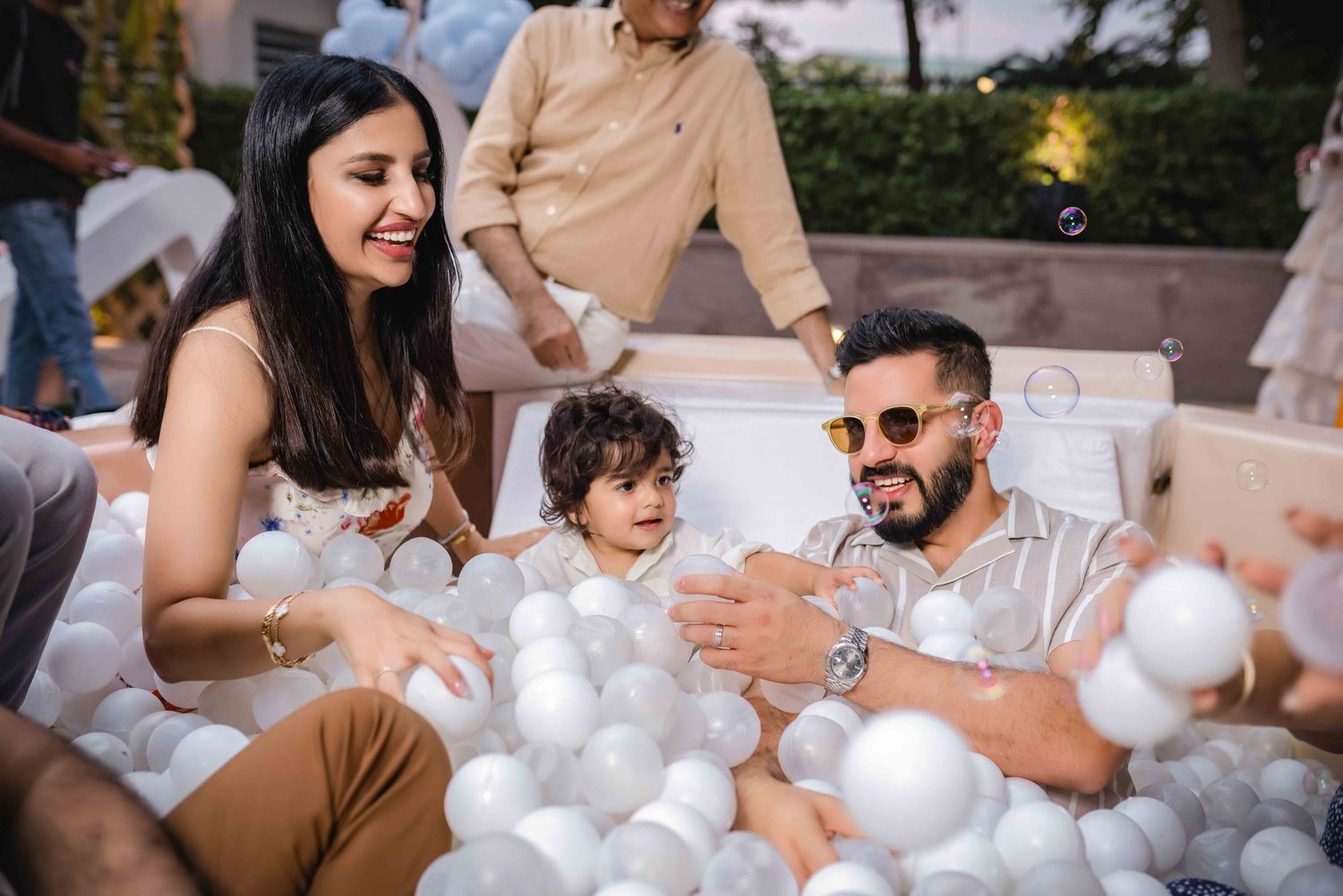 Family playing together in a white ball pit at an outdoor celebration party event.