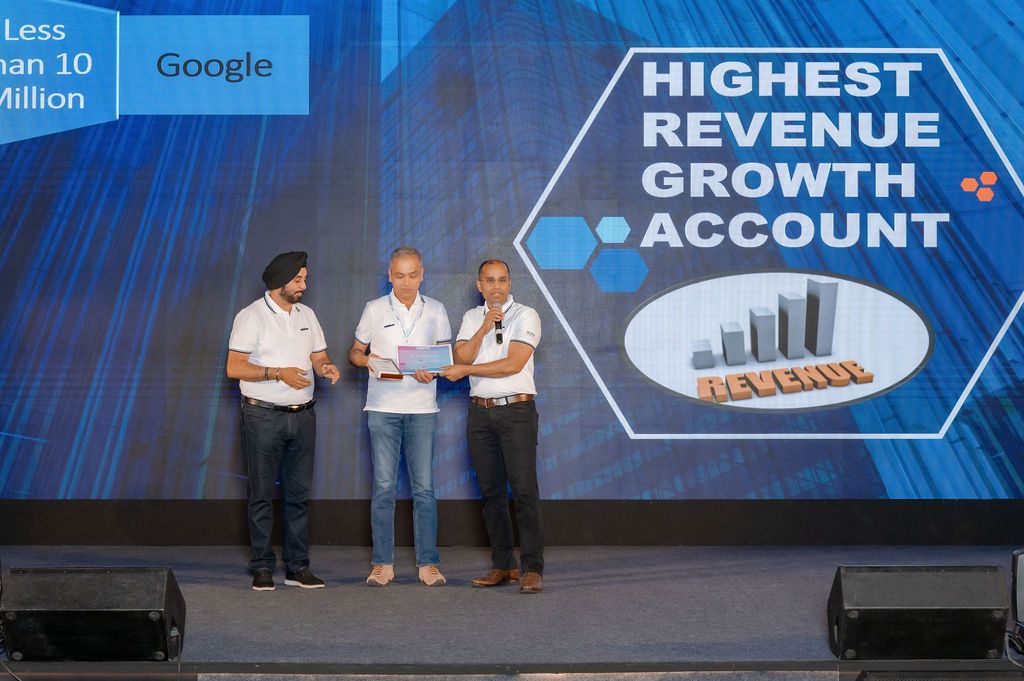 Three people stand on stage at an awards ceremony beneath a screen reading Highest Revenue Growth Account for Google.